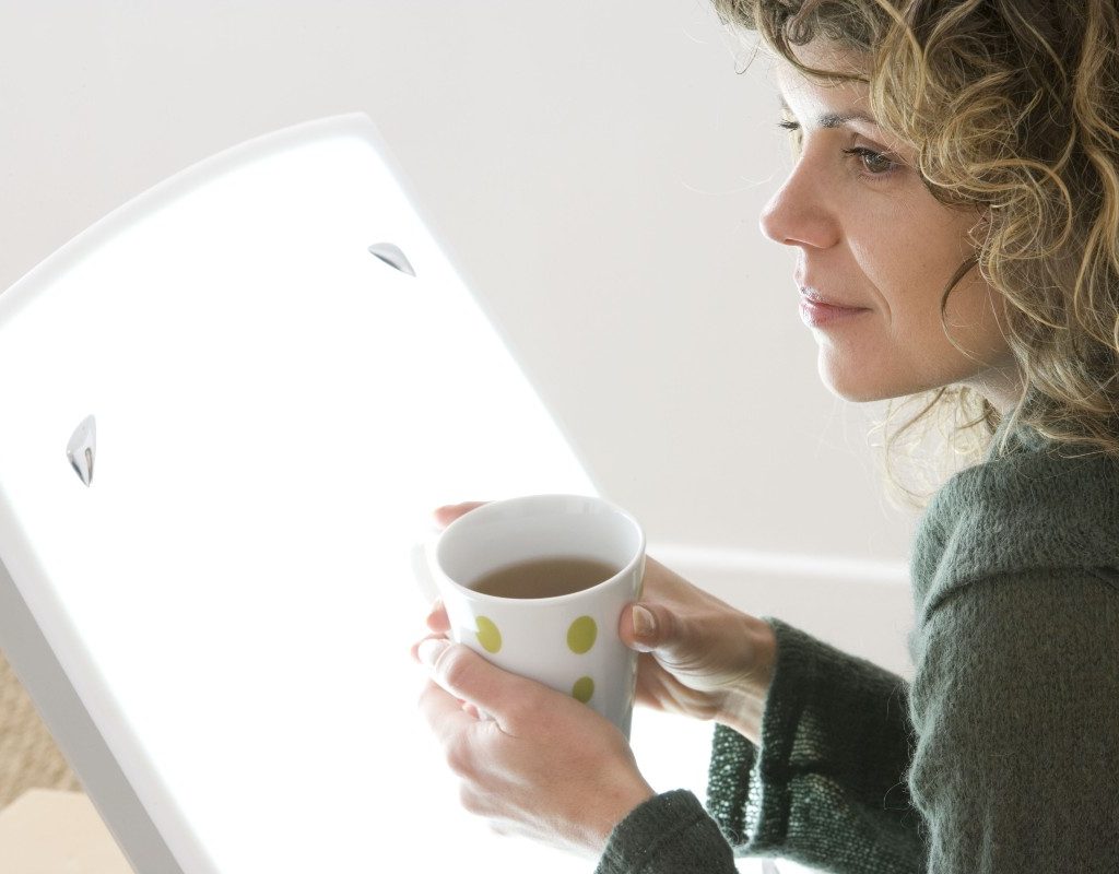 woman doing light therapy while drinking coffee