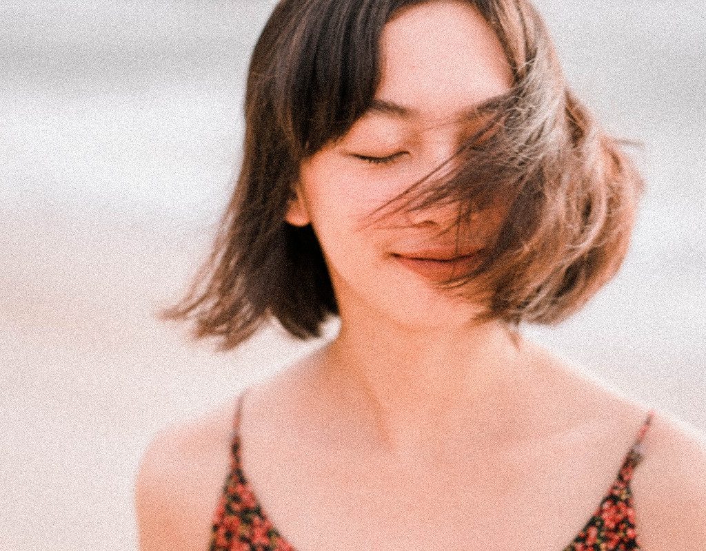 a woman with eyes closed walking outside