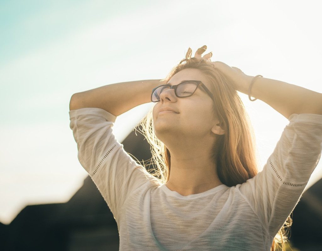 a woman outside with hands behind head