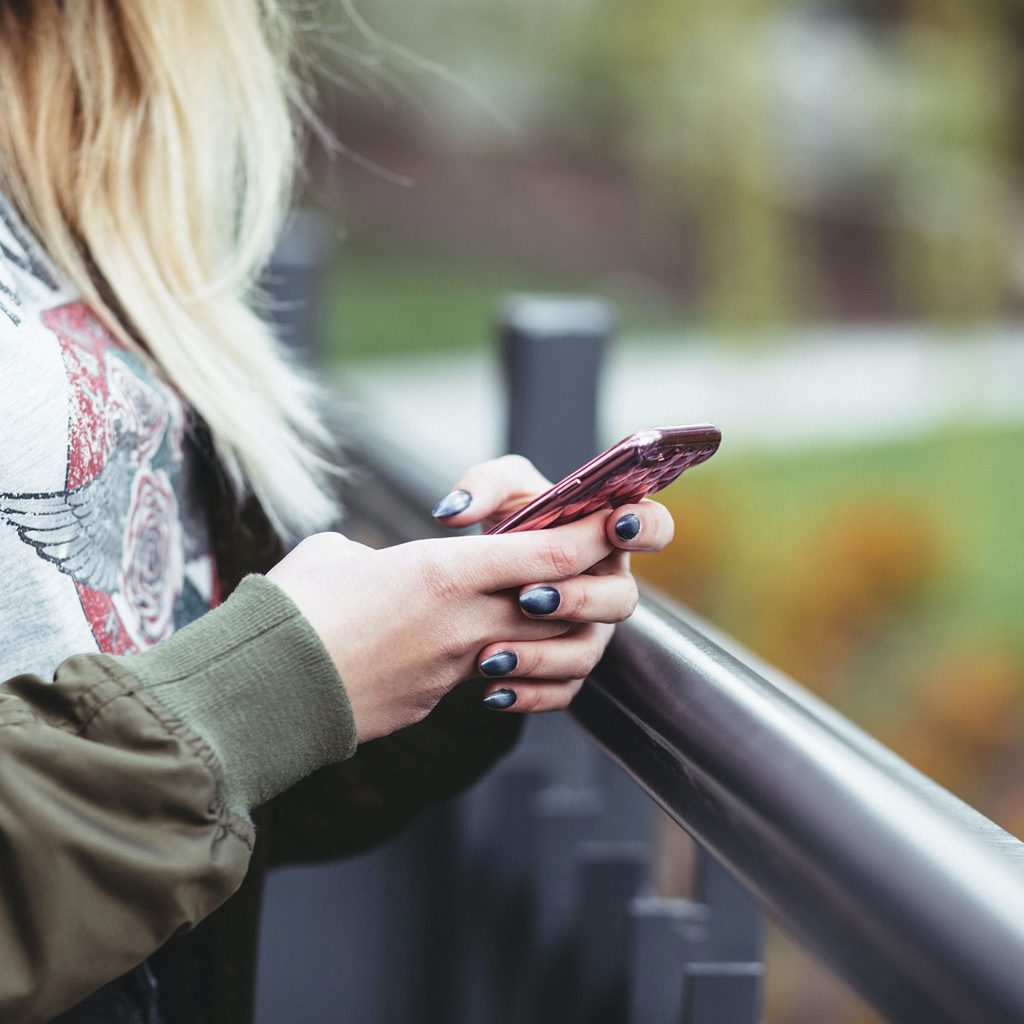 Woman standing outside looking at her phone
