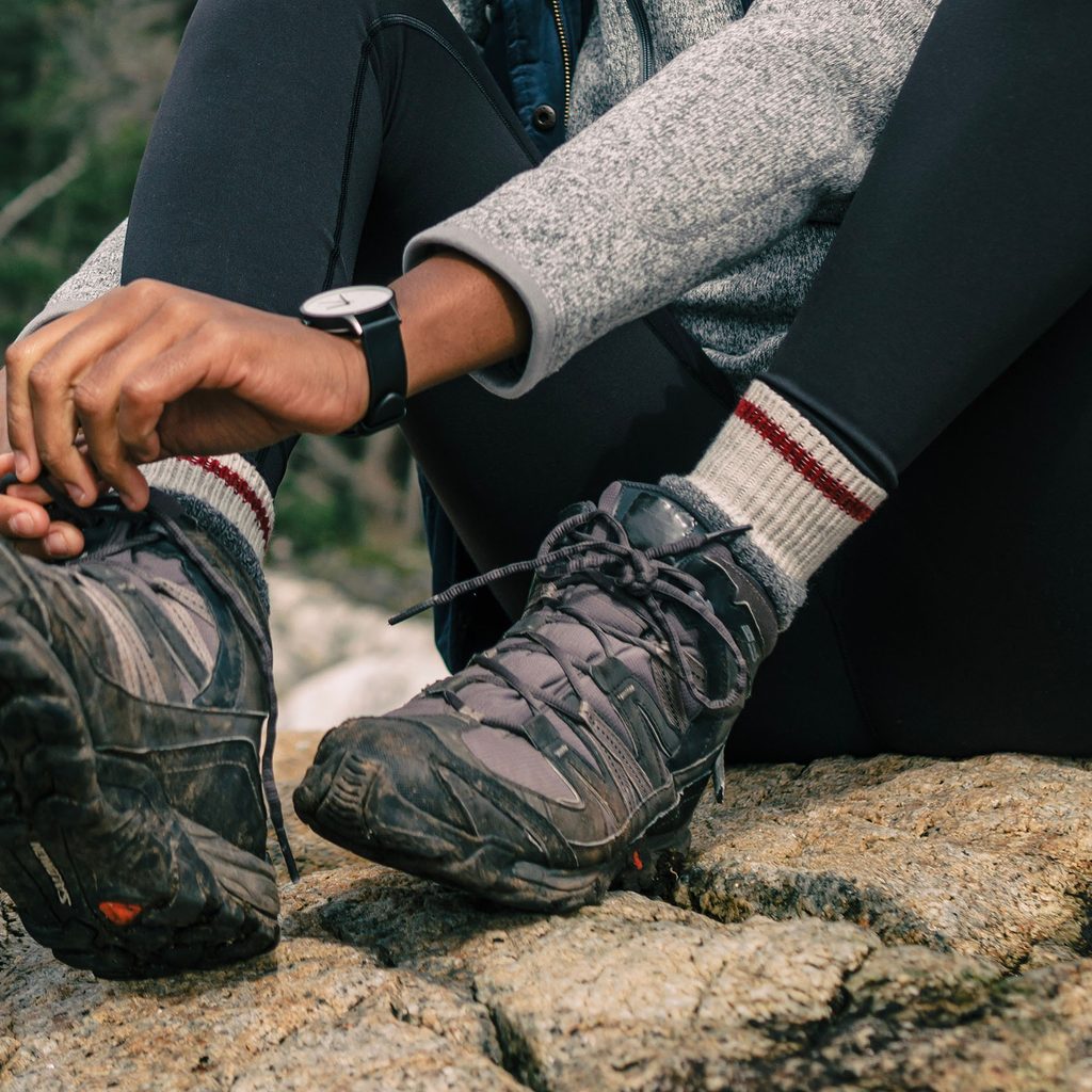 Woman tying hiking boots on a rock