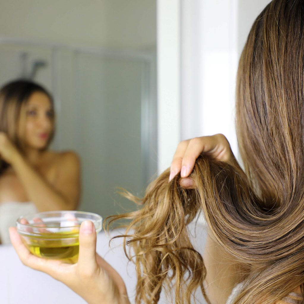 Woman using olive oil treatment on hair