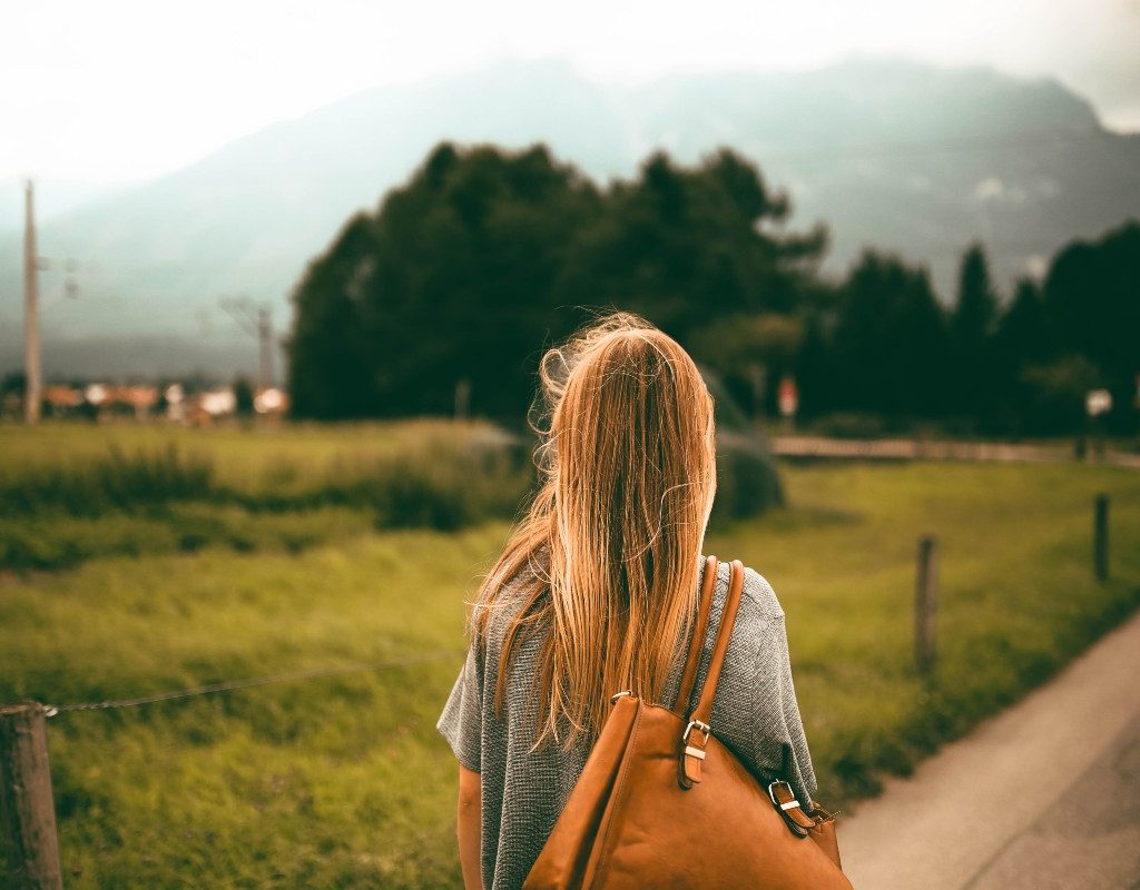 a woman with a brown bag walking outside