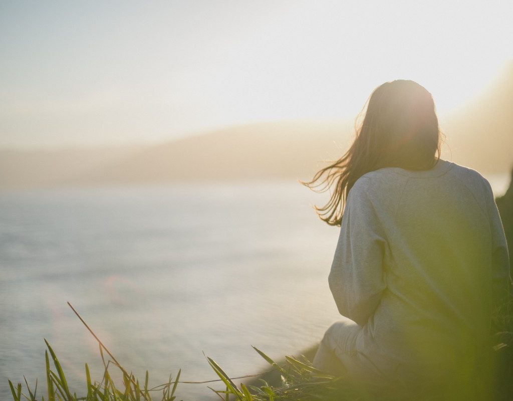 a woman looking out at the water at sunrise