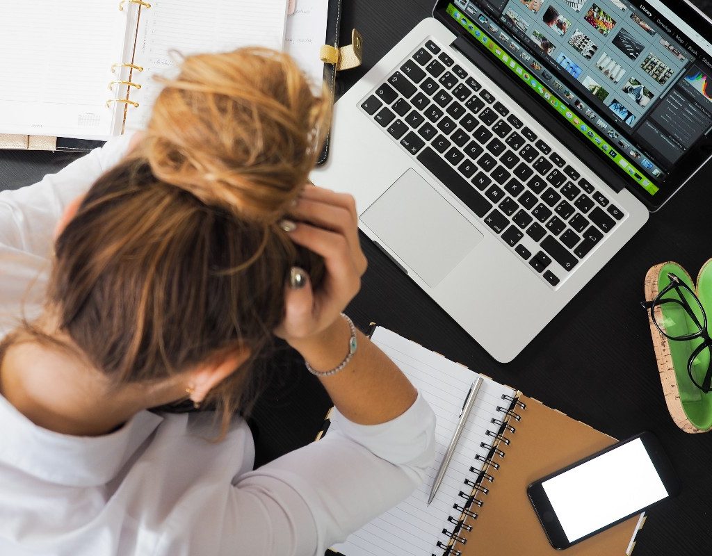a woman with her head in her hands sitting at her desk