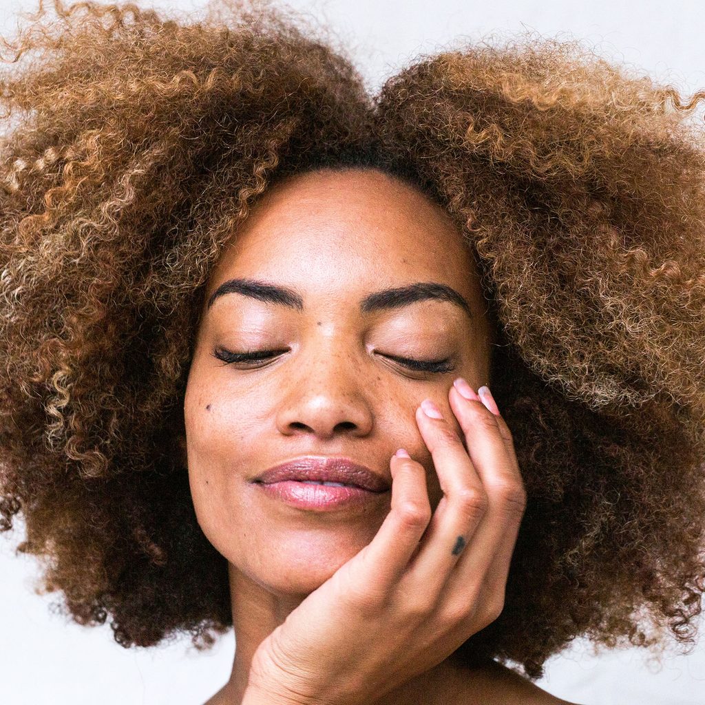Woman with natural hair and her hand on her face