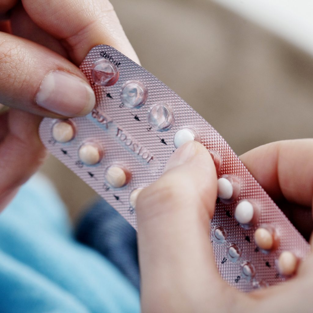 Woman's hands holding birth control pills