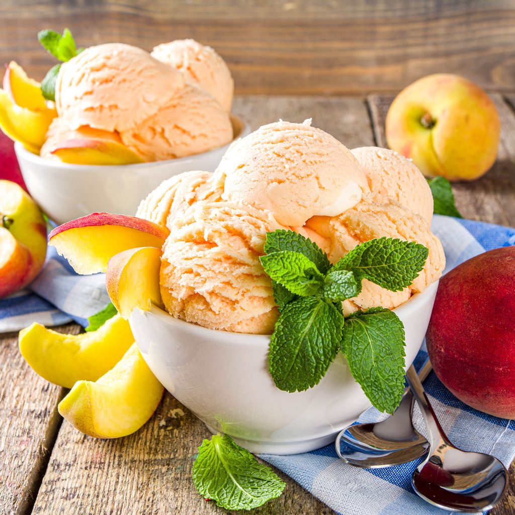 Peach ice cream in bowls with peaches