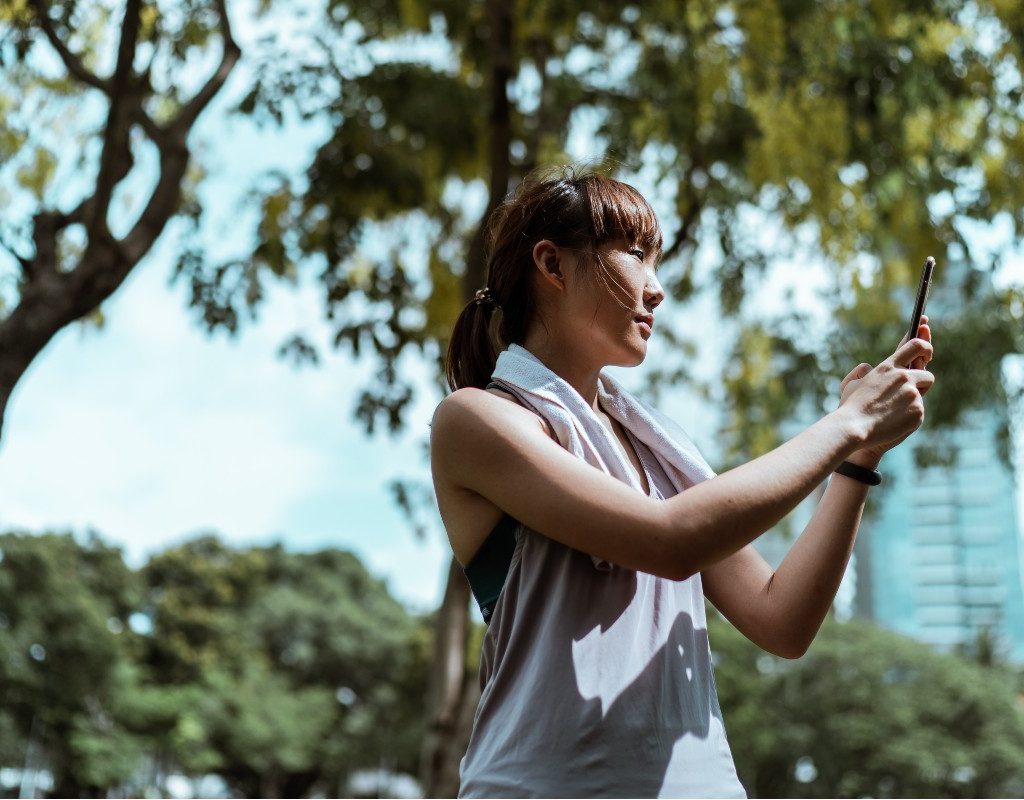 a woman in a park walking and looking at her phone