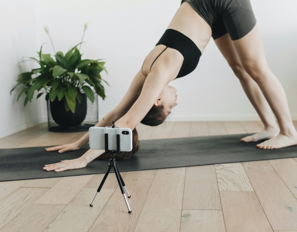 a woman in downward facing dog with her phone on a tripod