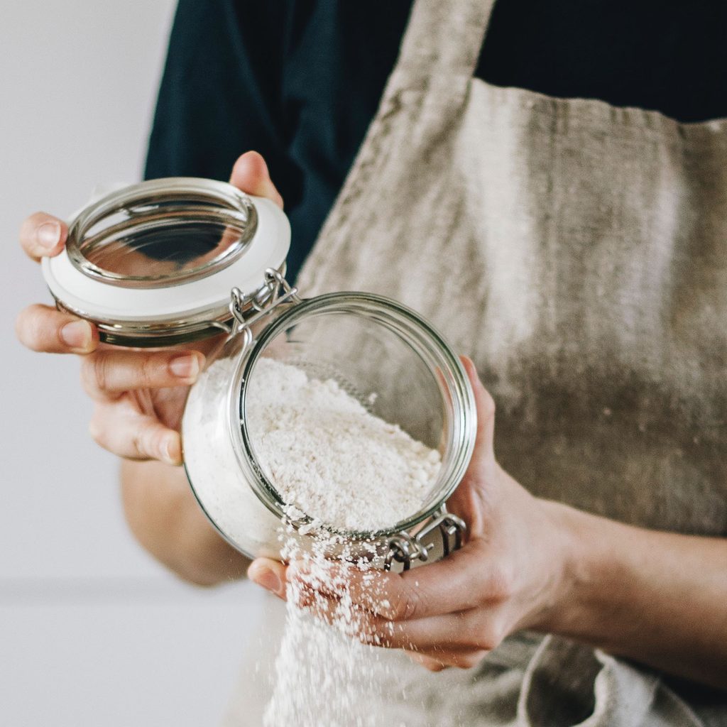Baker pouring flour into a bowl