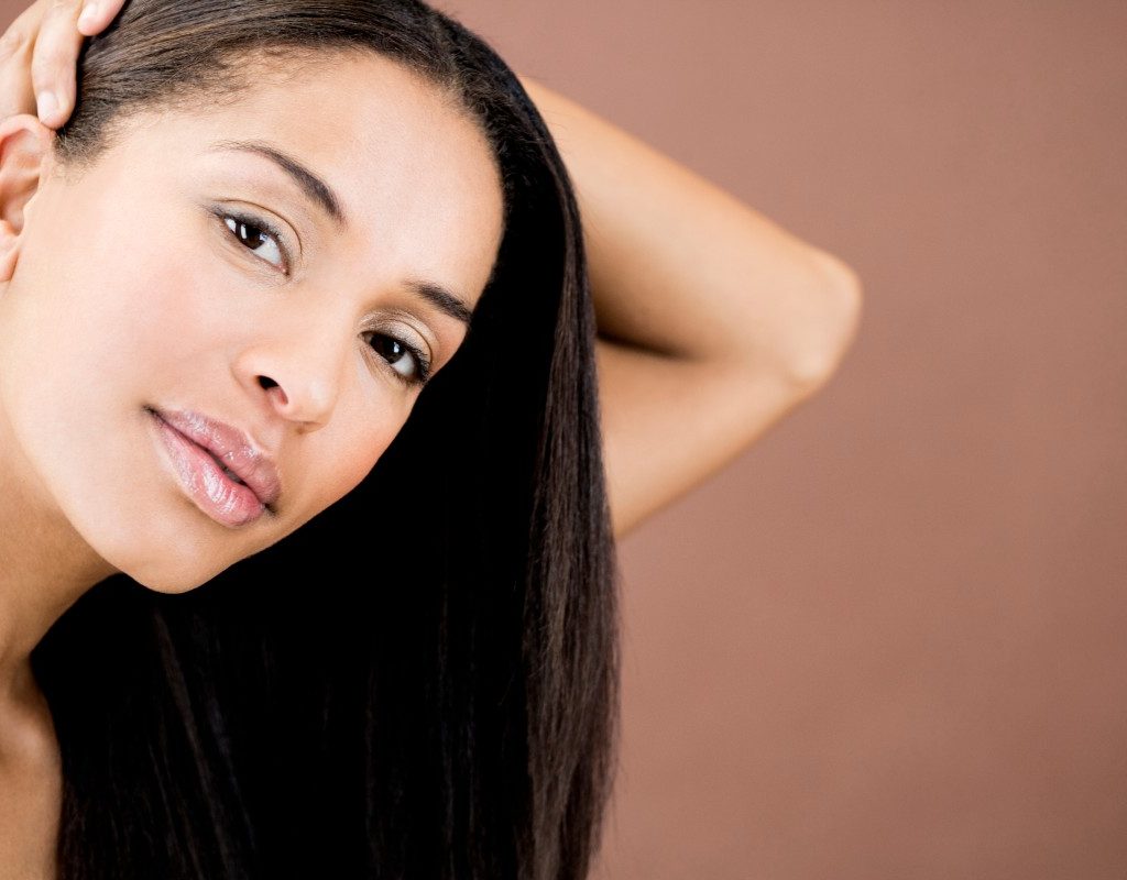 a beauty shot of a woman with straight hair against a brown background