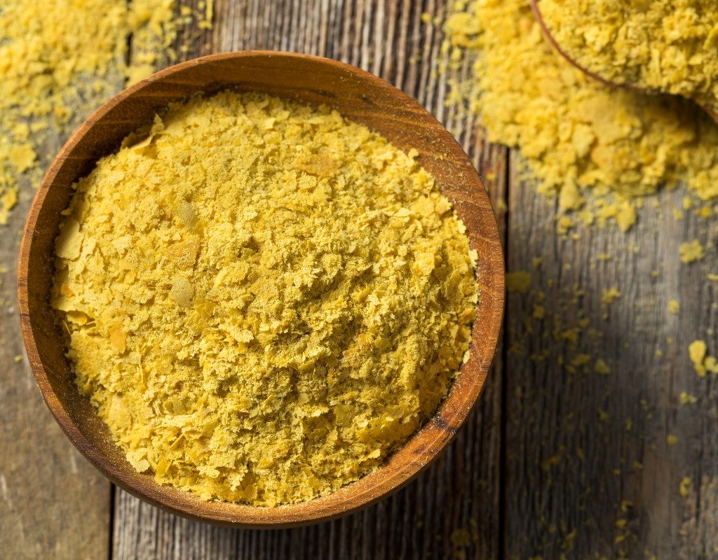 a bowl of nutritional yeast on a wooden table