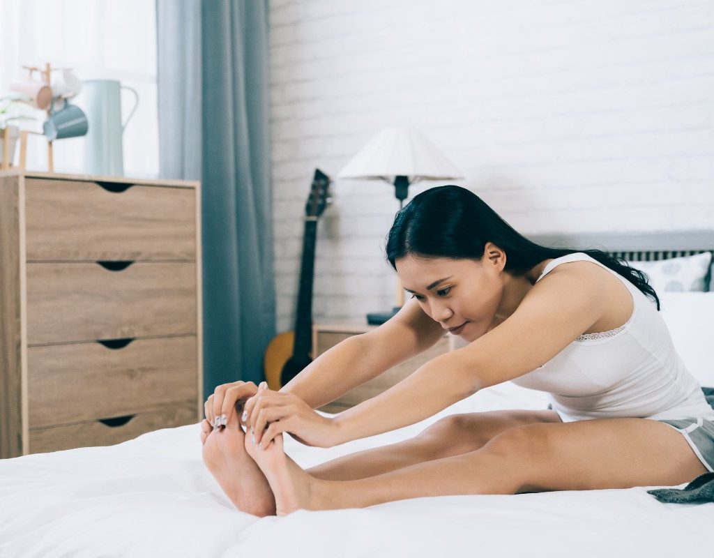 a woman doing forward fold from bed