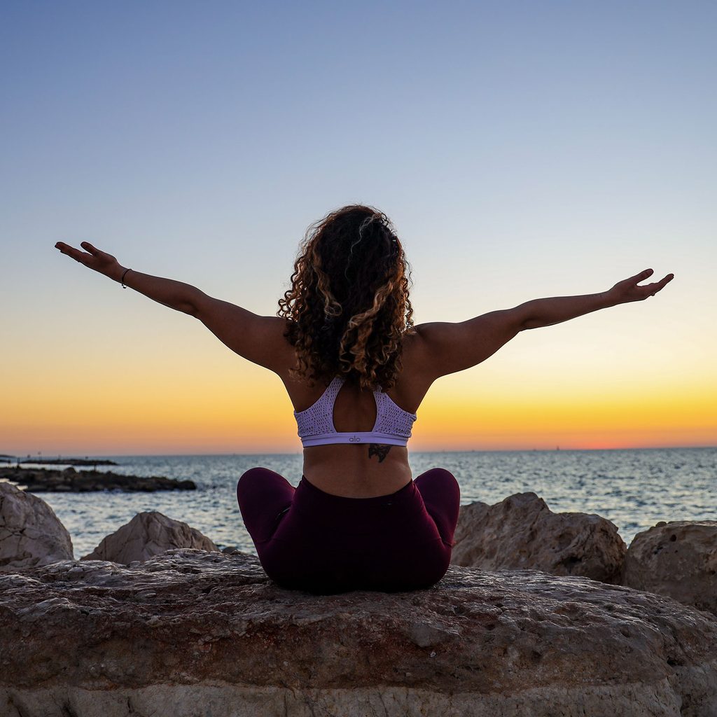 Relaxed woman doing yoga by the ocean