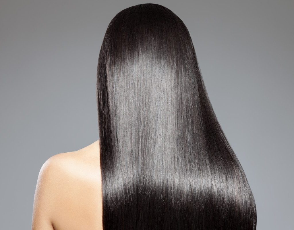 the back of a person's head. she has long, shiny, straight hair