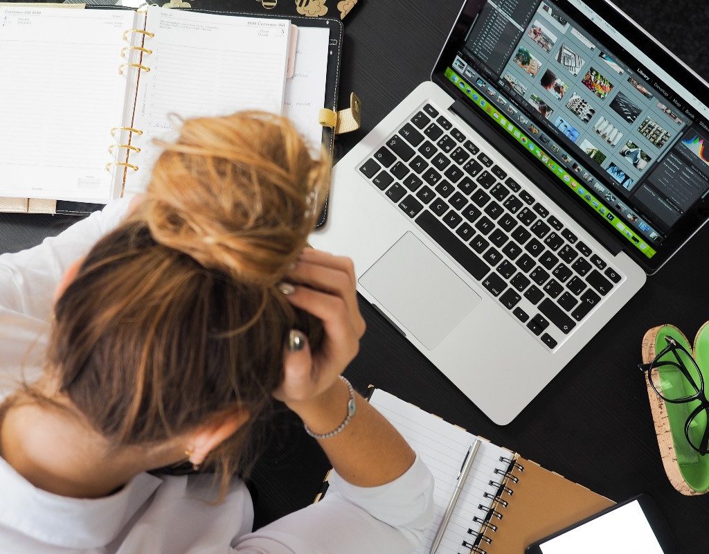 a stressed woman sitting at her desk with her head in her hands