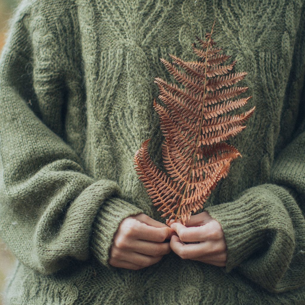 Woman wearing a green cable knit sweater