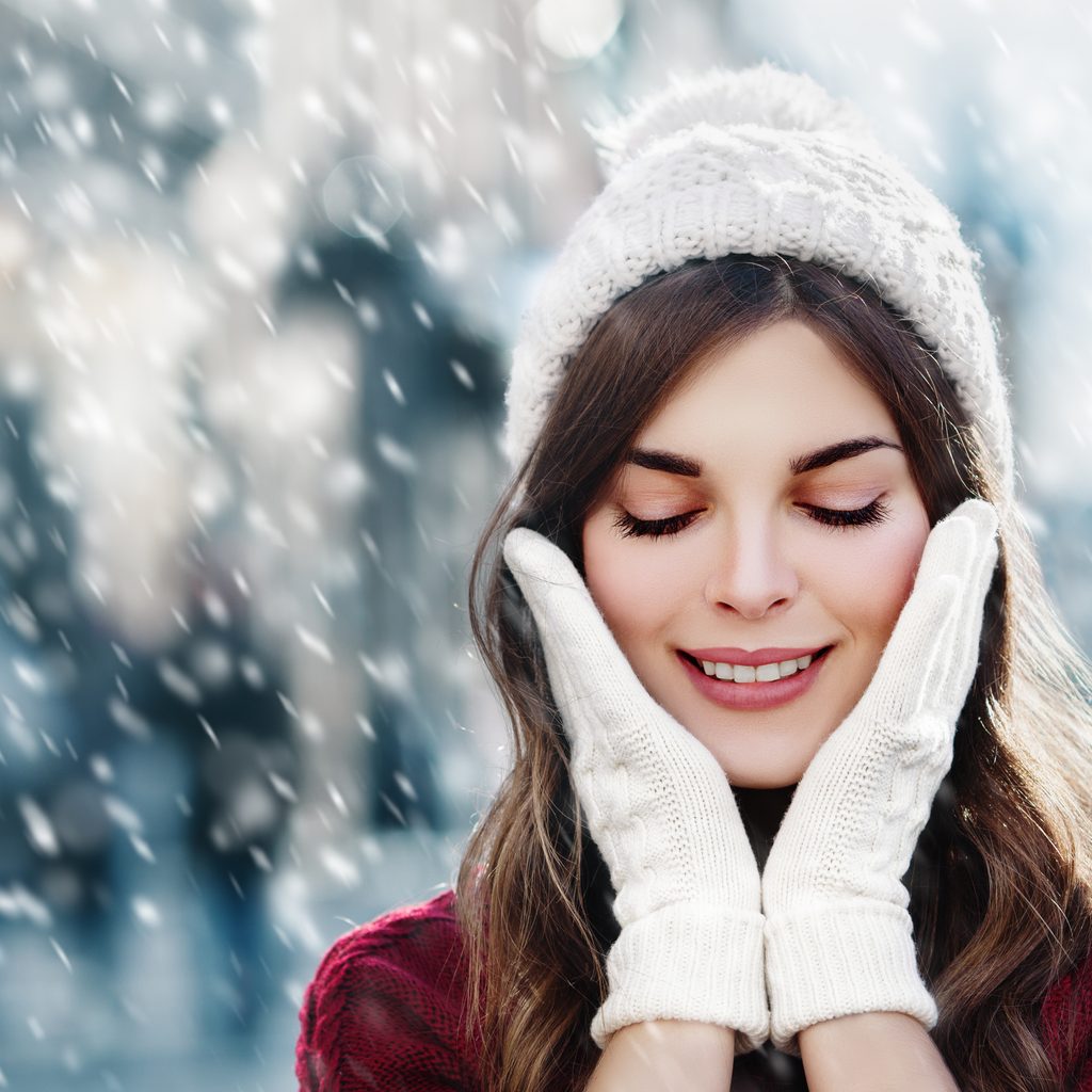 Closeup of woman in winter snowstorm with hands on face