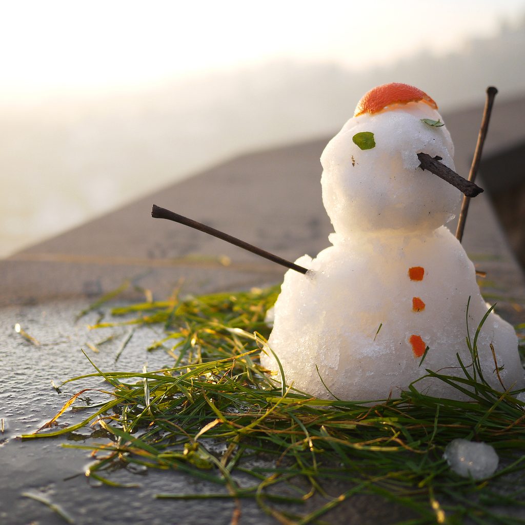 A melting snowman sitting on grass