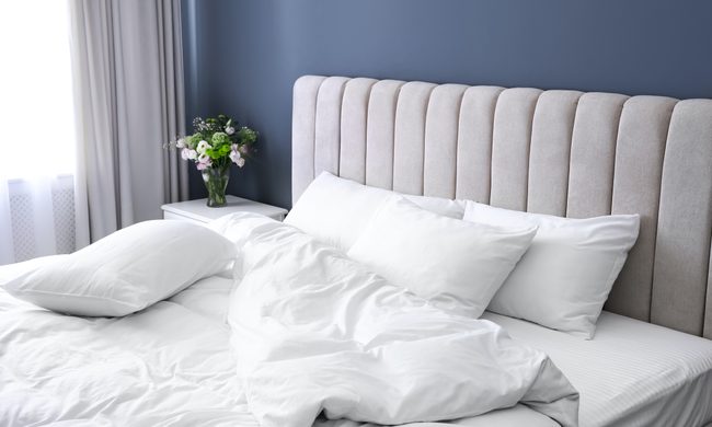 An unmade bed next to a bright window