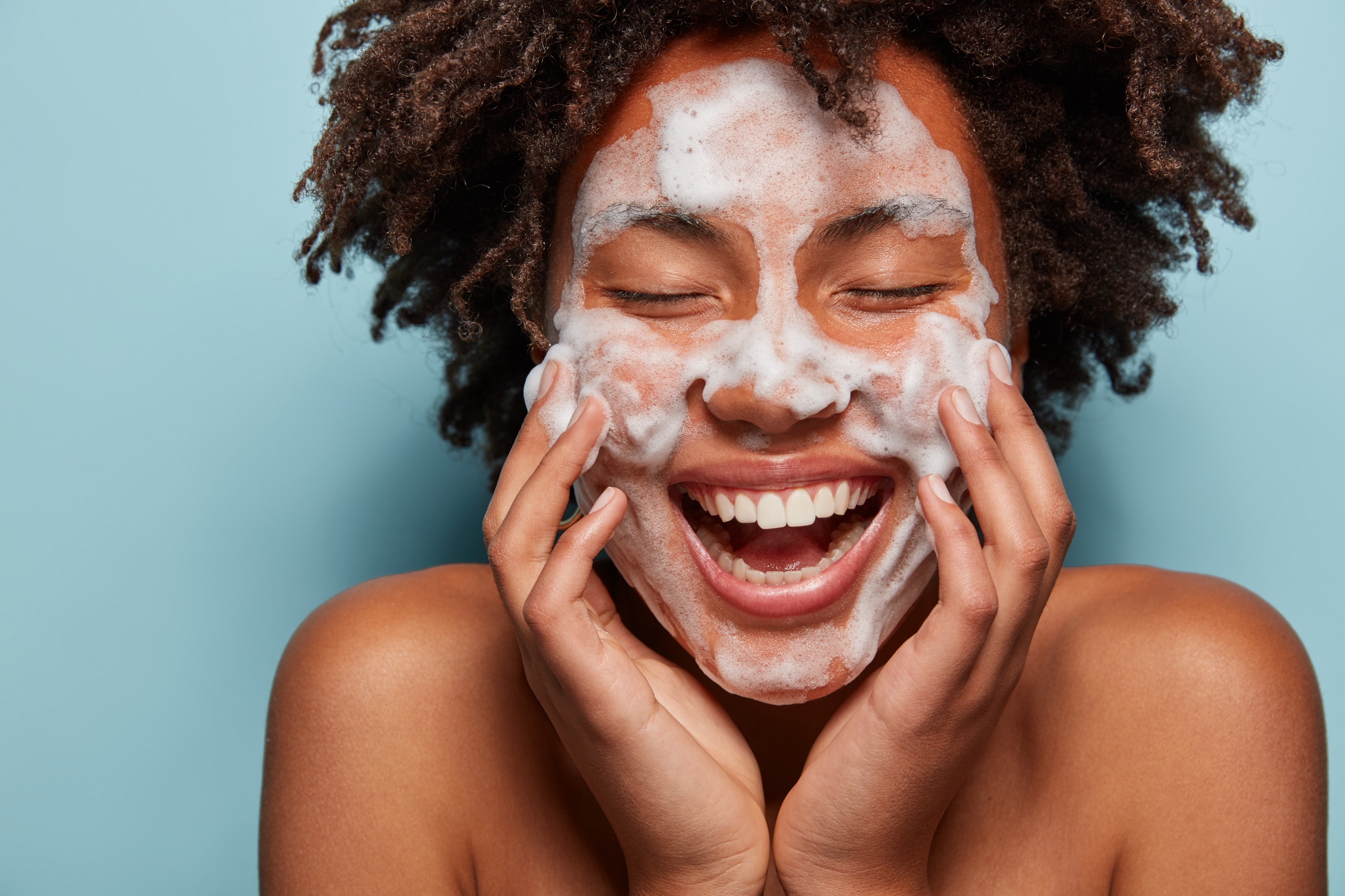 young woman with foam on her face during skincare routine