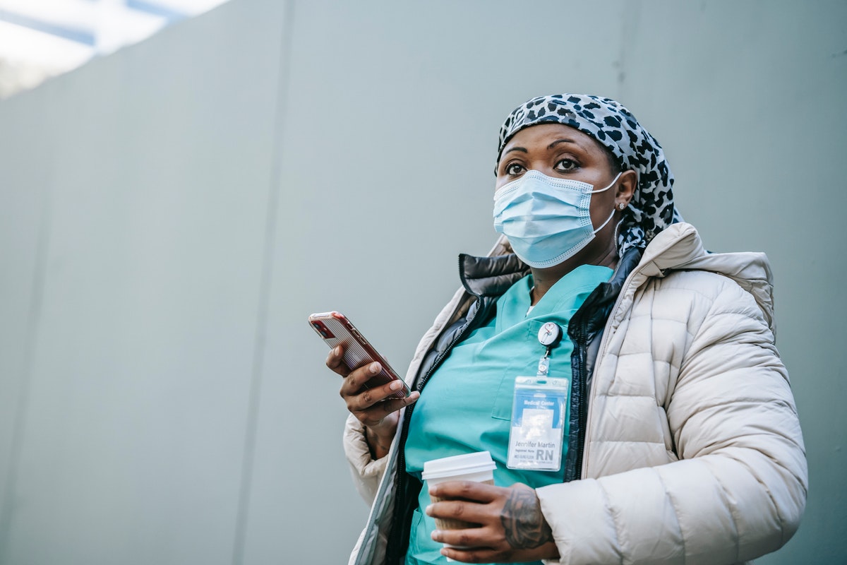 Healthcare worker wearing her mask with her iPhone in her hand