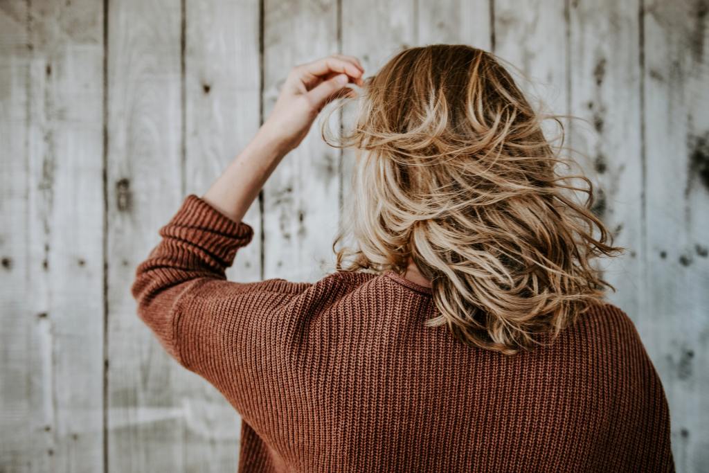 A woman tousling her blonde hair.