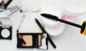 Closeup of a mascara wand with makeup in the background.