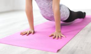 A woman doing yoga on a purple mat.