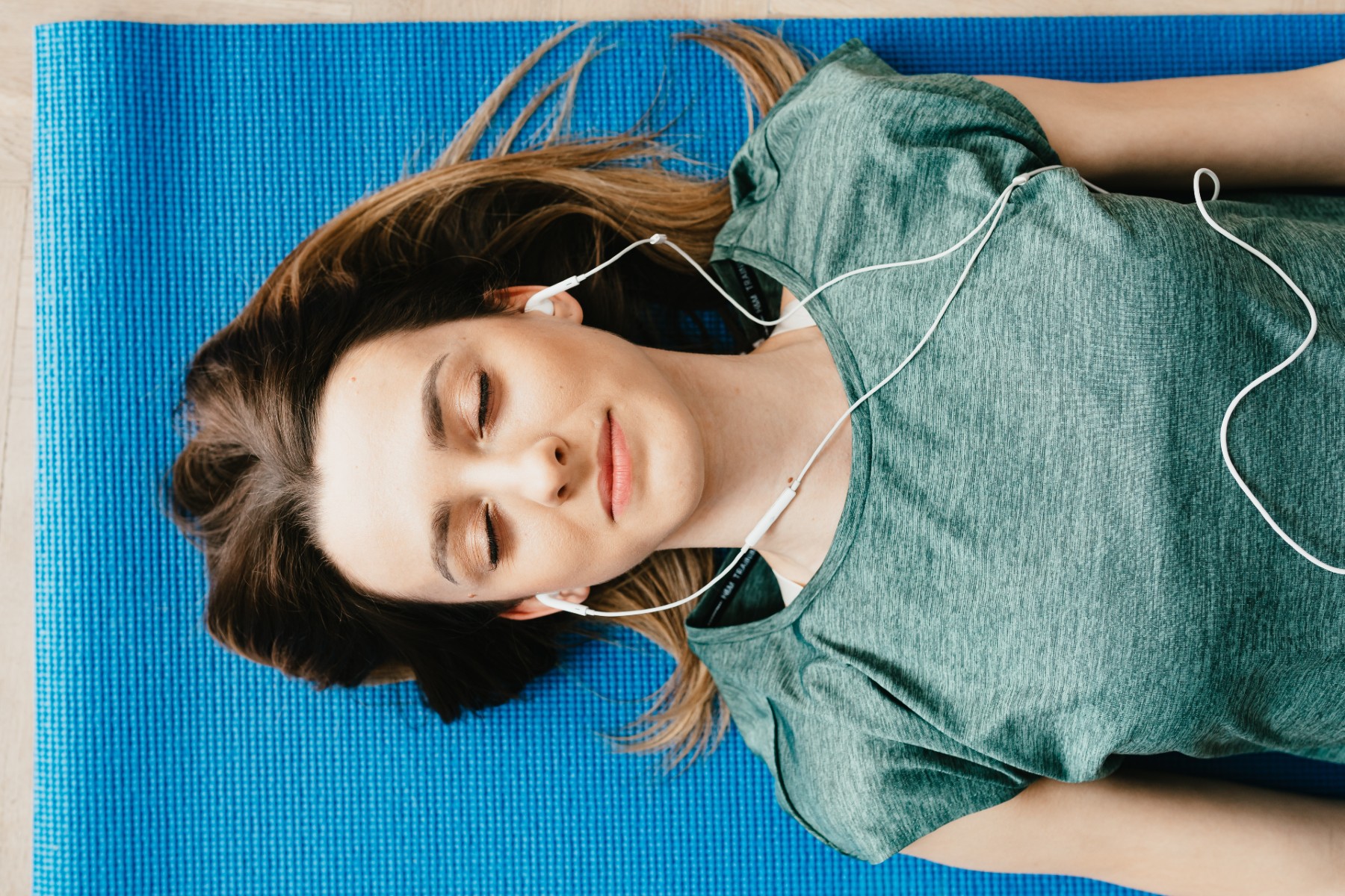 woman listening to music on yoga mat