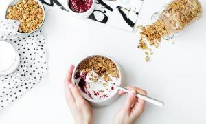 Woman with a bowl of yogurt and granola on a white background.