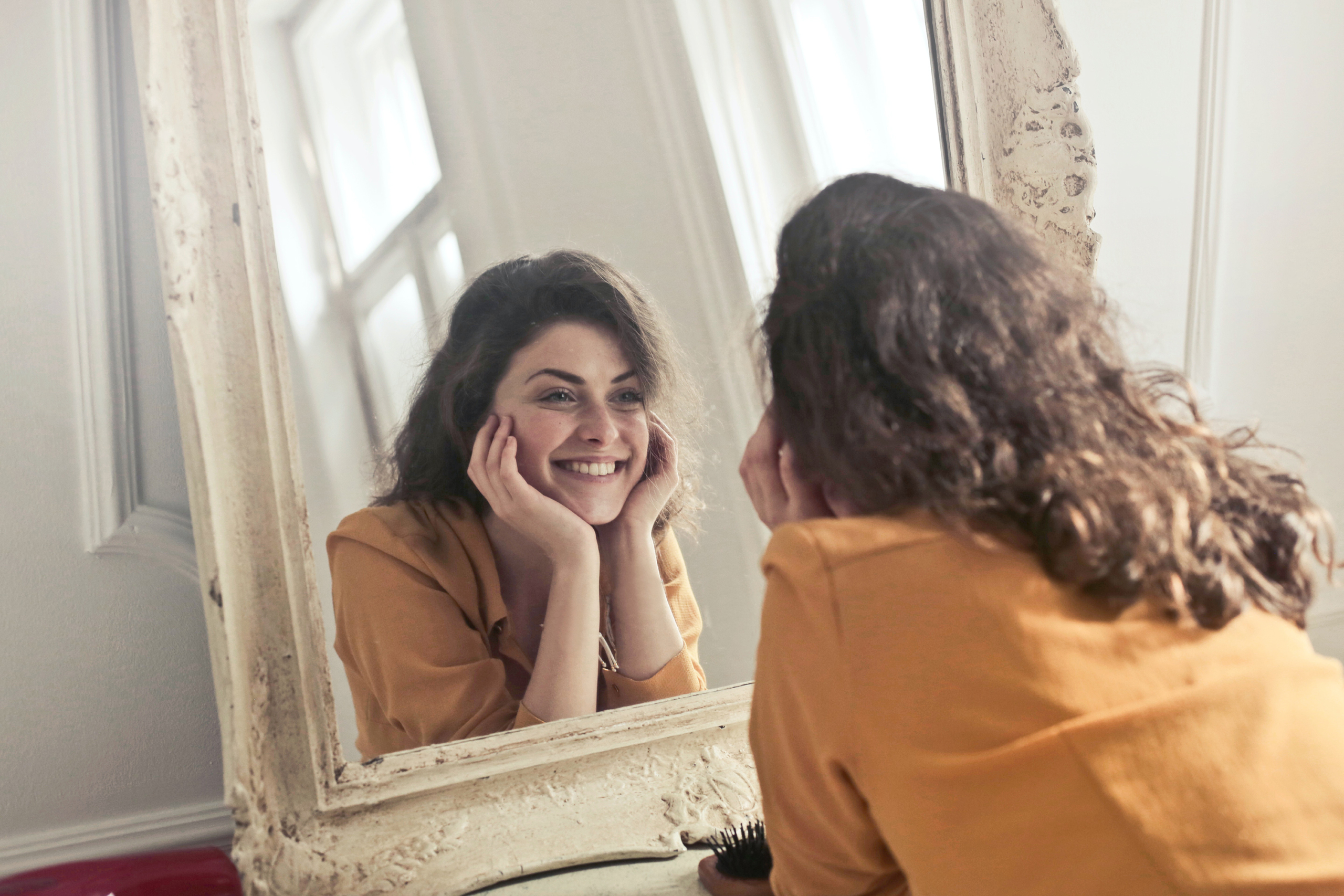A young woman smiling at herself in the mirror