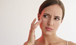 woman touching her face due to pores