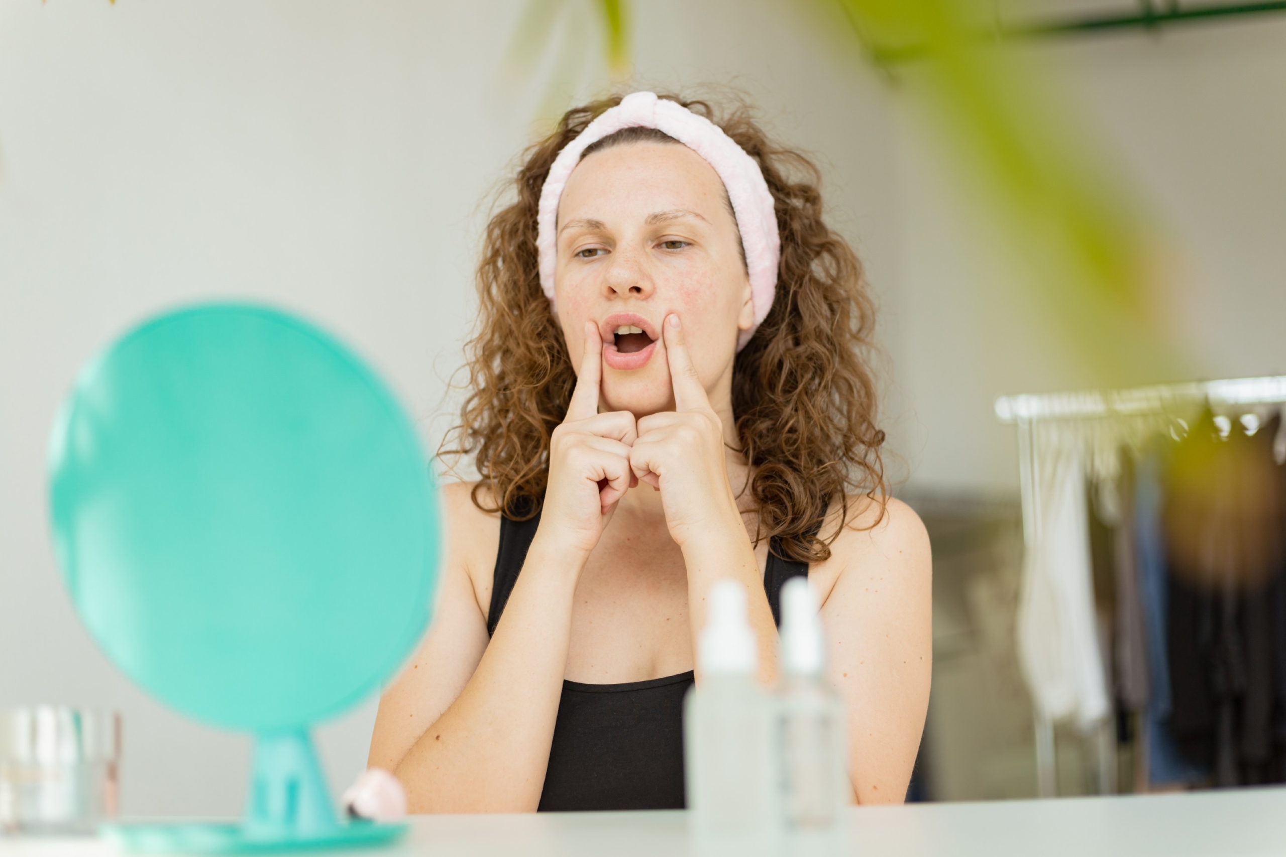 woman practicing face yoga in front of mirror