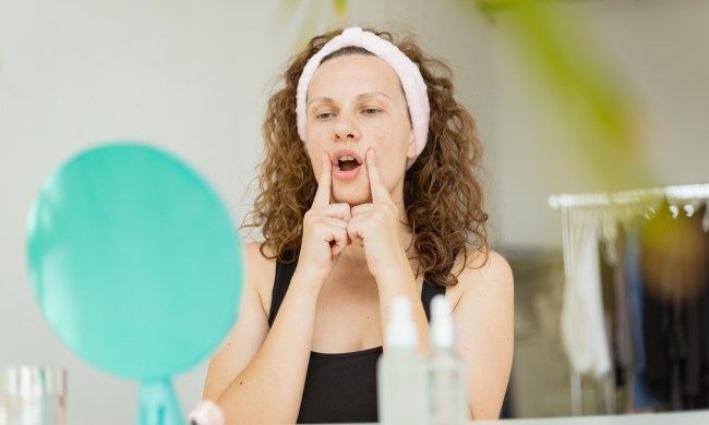 woman practicing face yoga in front of mirror