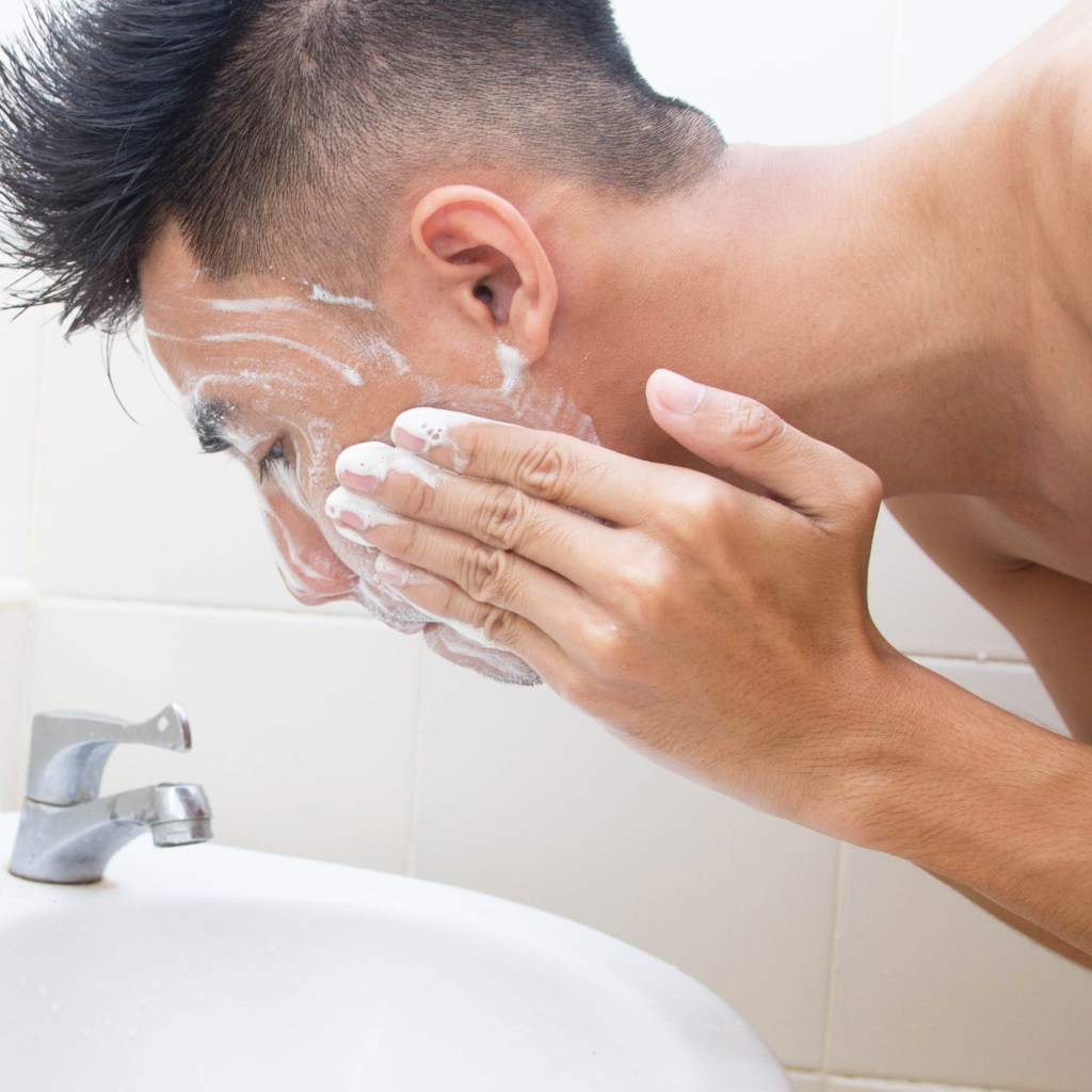 young man cleansing face in sink