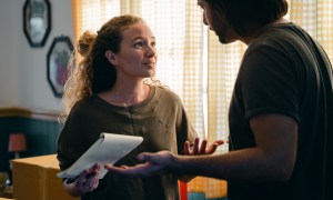 a couple argues in their living room with their arms up in confusion