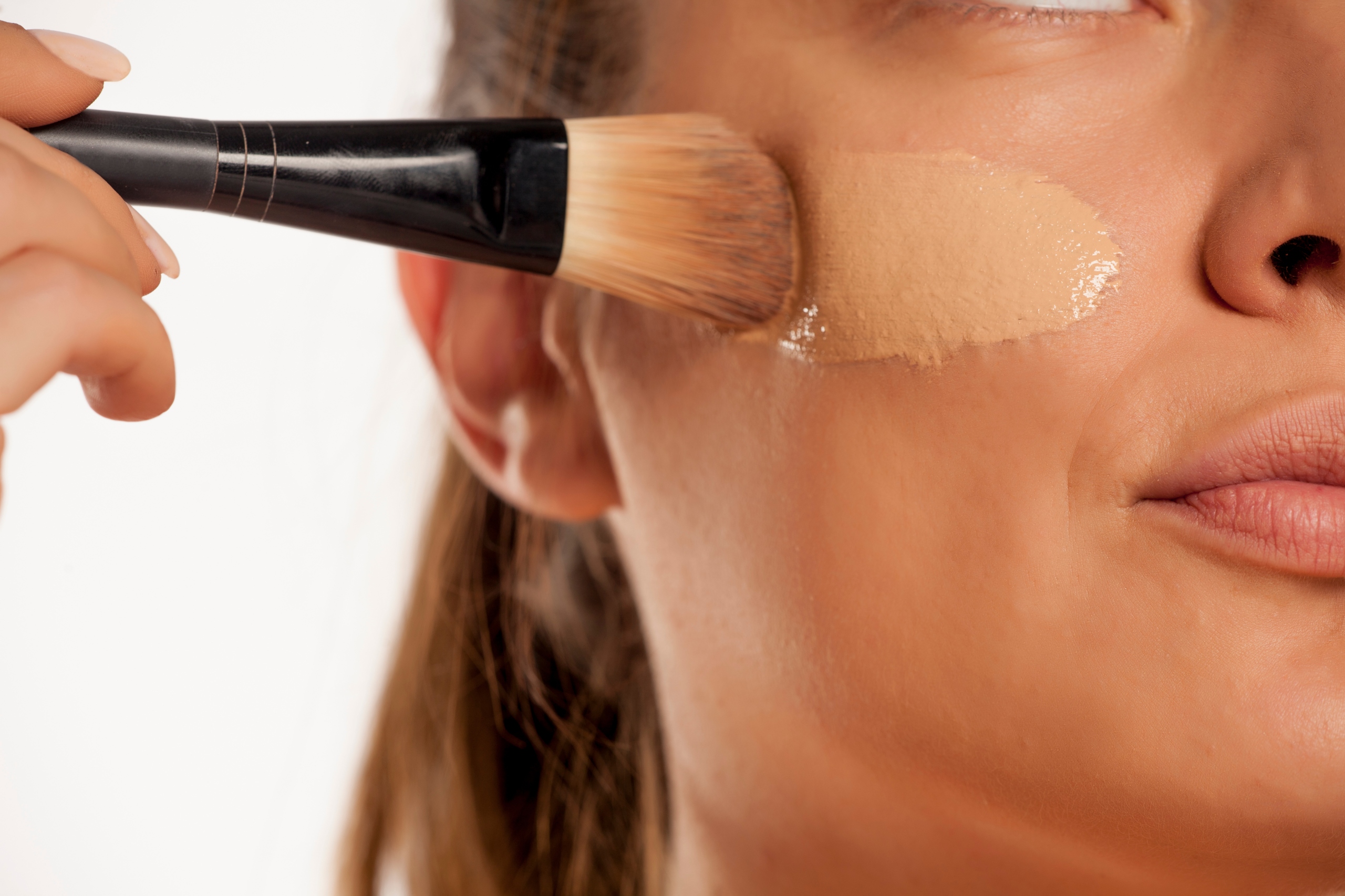woman applying foundation to cheek with brush
