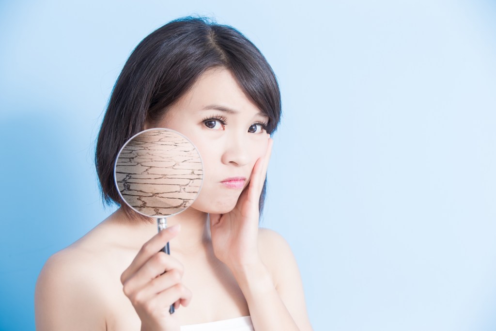 woman using magnifying glass to show dry skin