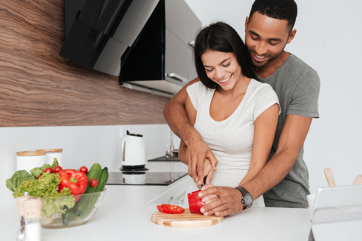 A couple chops a tomato