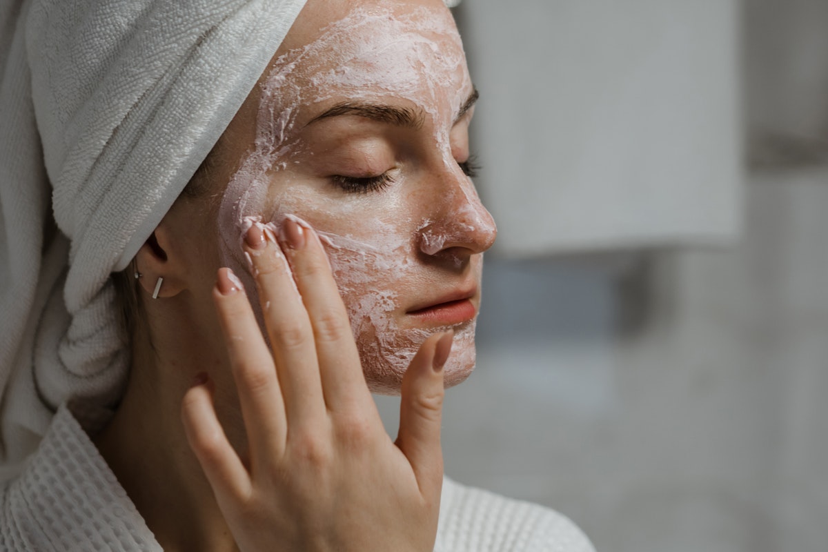 A woman applying an exfoliator to her face