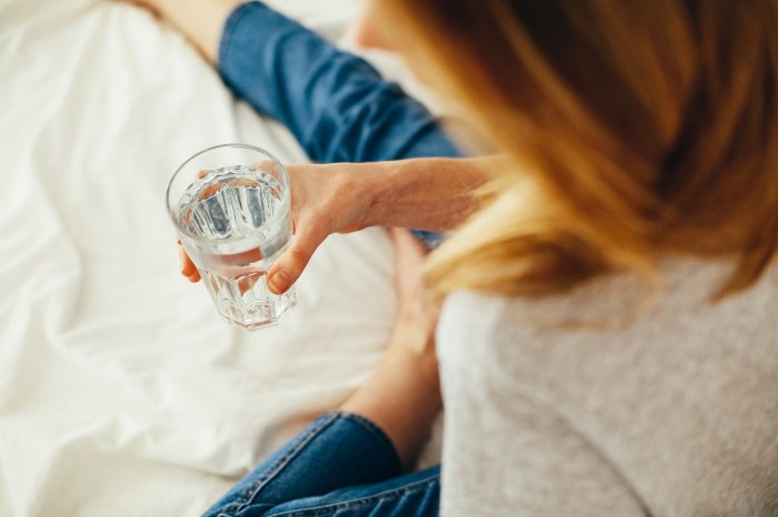 woman-drinking-water-on-white-blanket