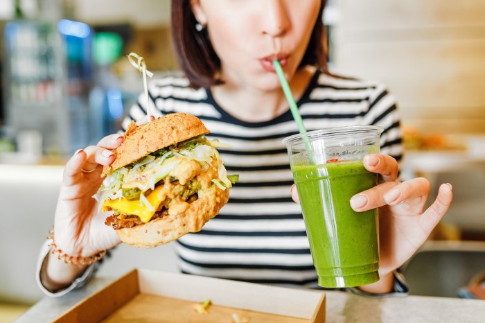 young woman eating a veggie burger and green smoothie