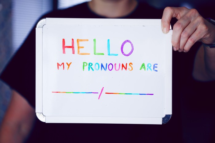 Person holding a sign declaring pronouns