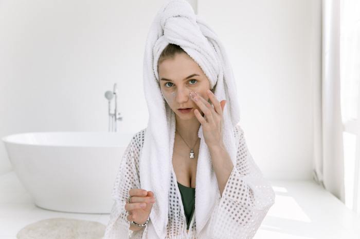 A woman applying skincare products to her face.