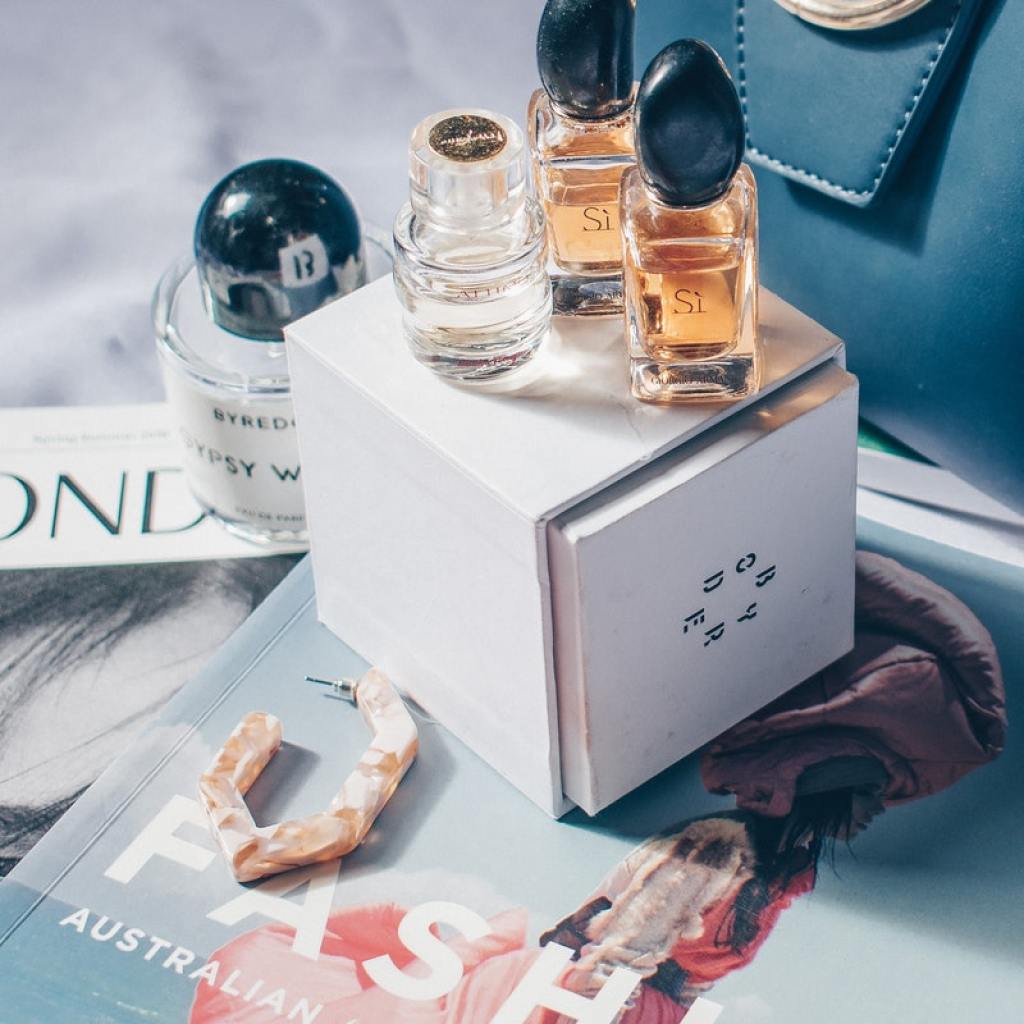 Perfume bottles displayed on a box that is on top of magazines.