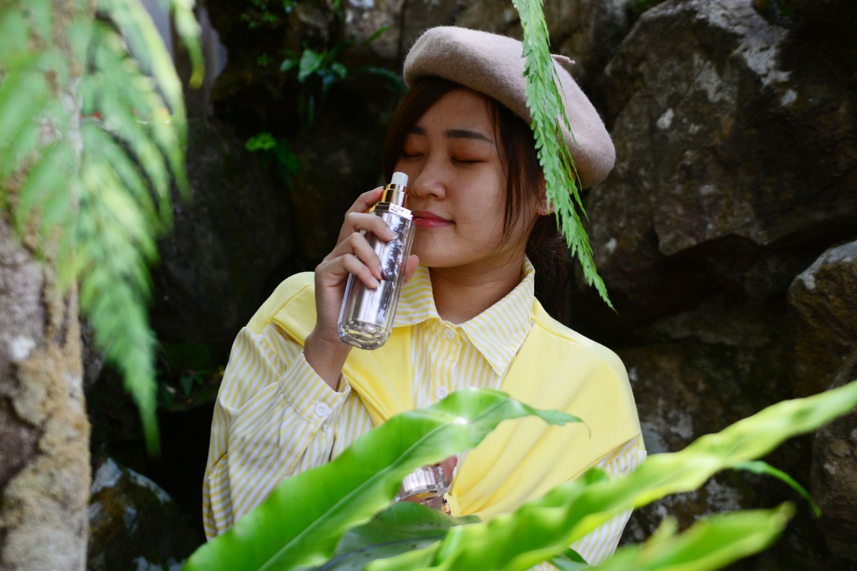Woman outside smelling a perfume.