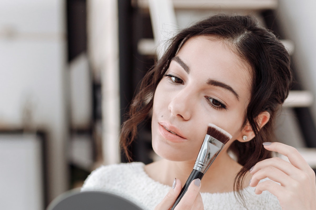 A woman putting on makeup in front of a mirror.