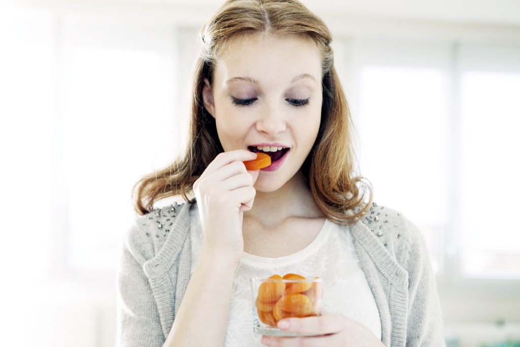 A woman eating dried apricots